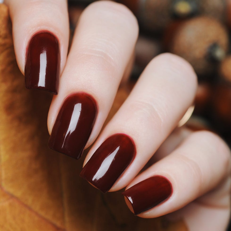 burgundy brown manicure with yellow leaf on a background of acorns