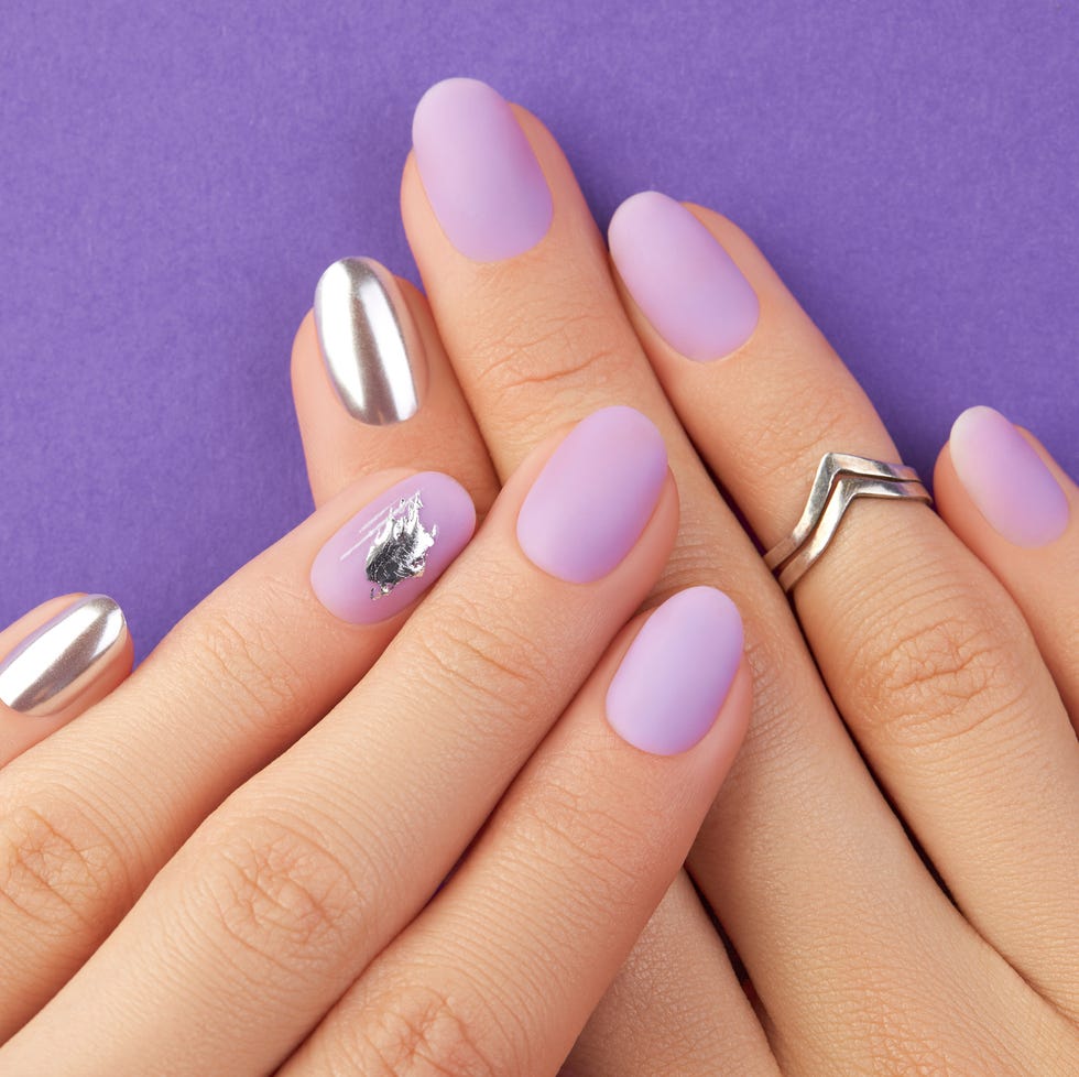 close up womans hands with matte lavender nail design on purple background manicure, pedicure beauty salon concept