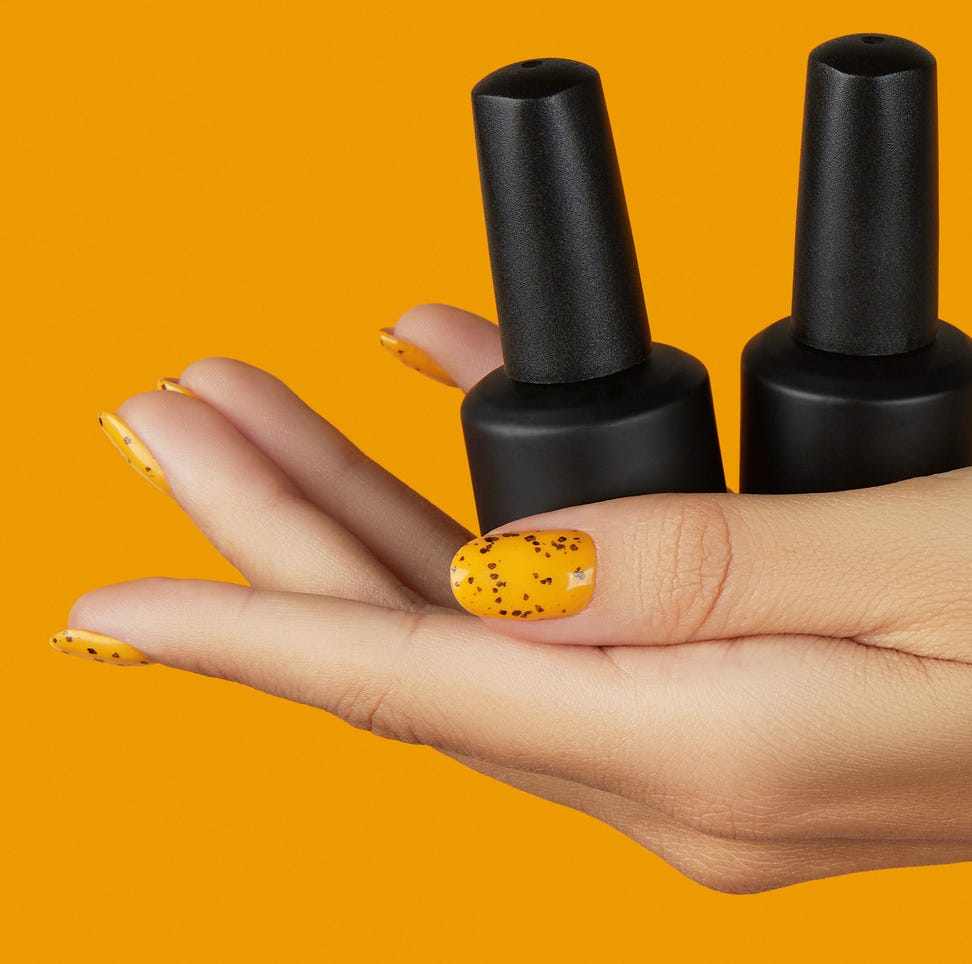 manicured womans hand holding nail varnish bottle on orange background beauty salon template trendy nail design