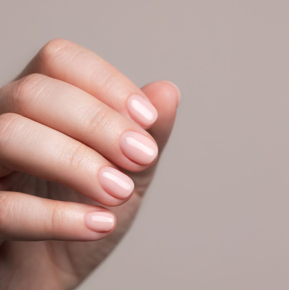 female hand with beautiful manicure pink nude gel nails nail care concept