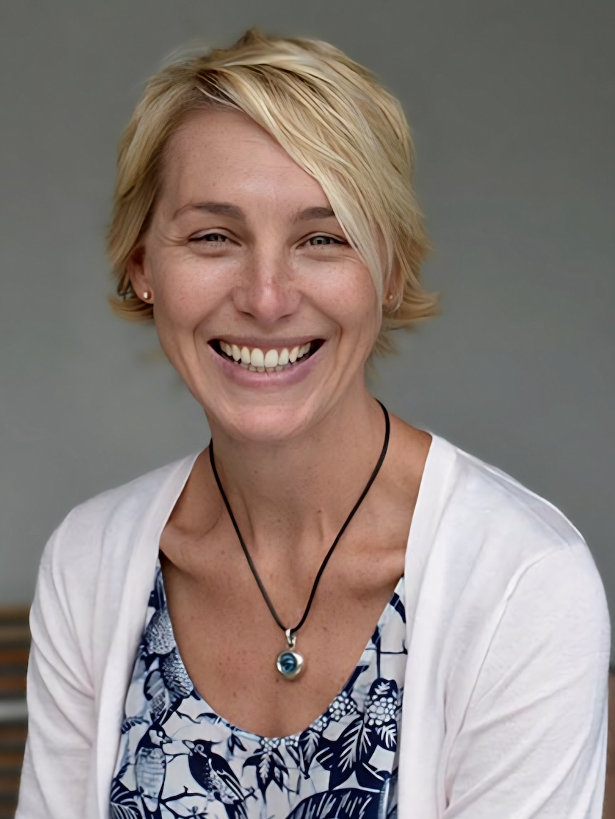 A blonde woman in a blue and white top smiling