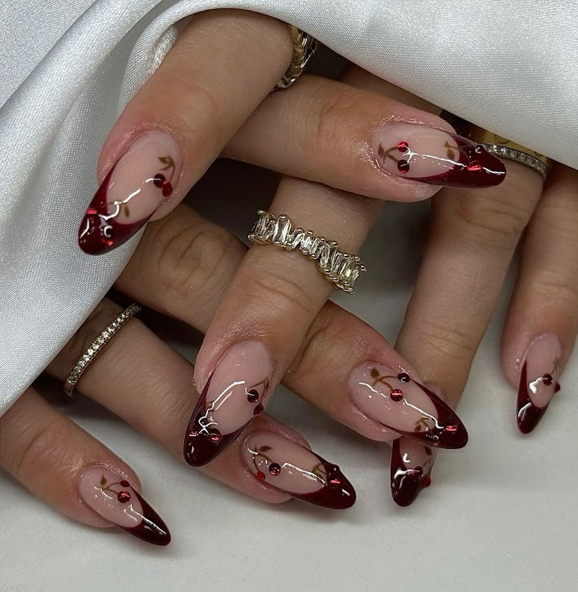 Cherry mocha French tip nails with rhinestone-studded cherries are on-trend for fall 2024.