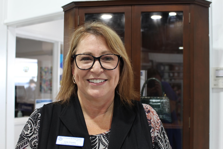 A middle aged woman with blonde hair smiles into camera 