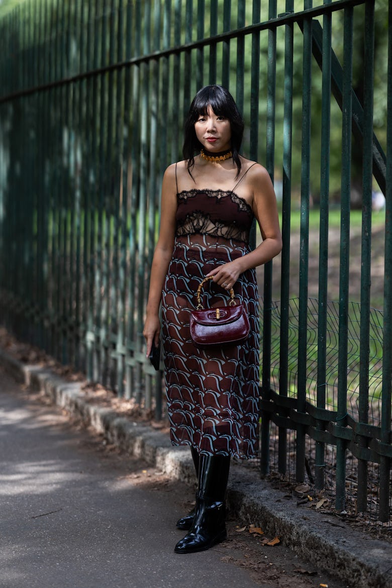 Susie Lau wears a light blue and burgundy printed midi dress, black leather boots and a Gucci bamboo...