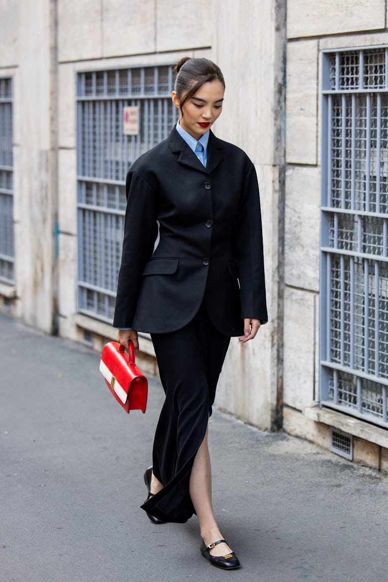 MILAN, ITALY - SEPTEMBER 21: A guest wears black skirt, blazer, red bag outside Bally during the Mil...