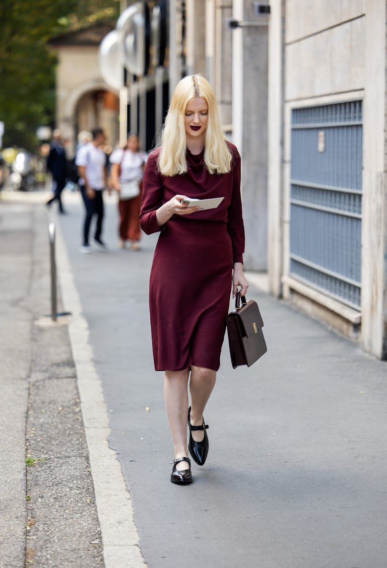 MILAN, ITALY - SEPTEMBER 21: Elodie Russel wears burgundy dress, brown bag outside Bally during the ...