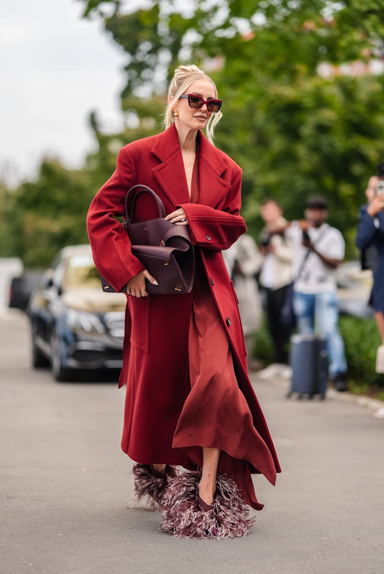 MILAN, ITALY - SEPTEMBER 21: Leonie Hanne wears dark red sunglasses, dark red wool Ferragamo coat, d...