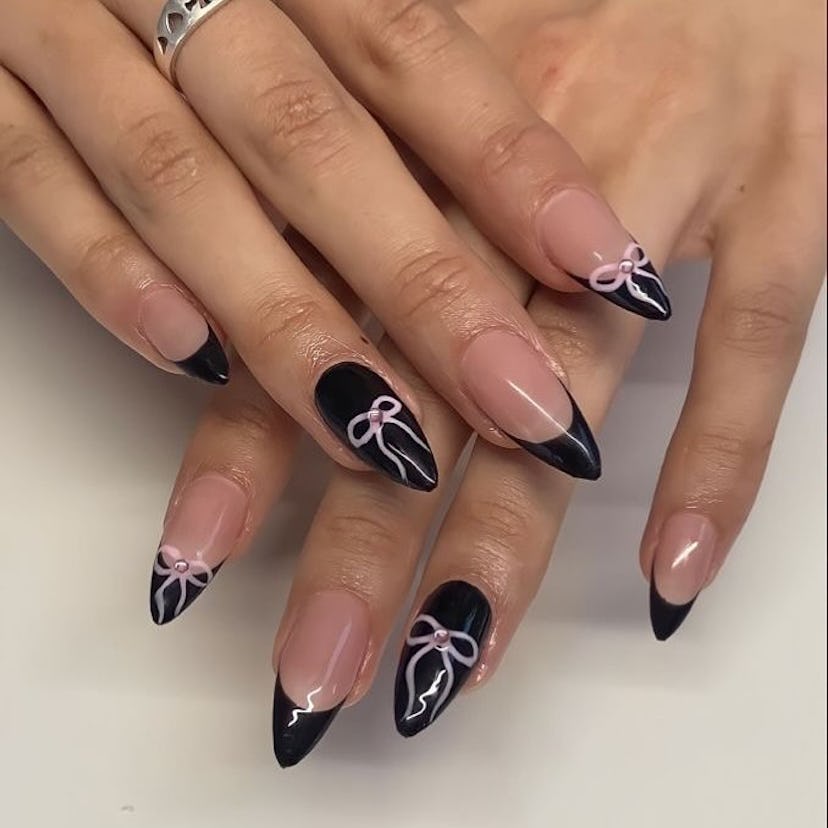 Black nails with pastel pink ribbon art matches the the dark coquette trend.