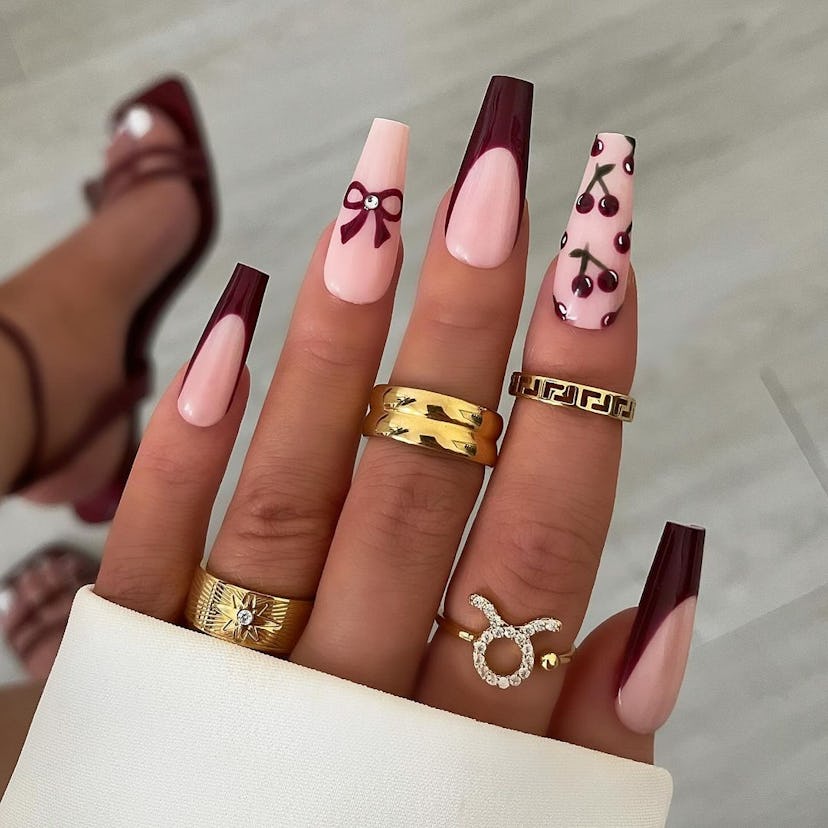 Burgundy nails with ribbon and cherry art matches the the dark coquette trend.