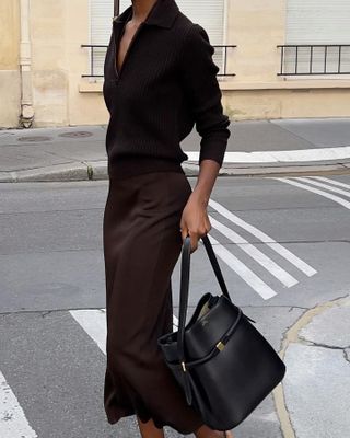 Woman wears brown jumper, brown silk skirt and brown Toteme handbag