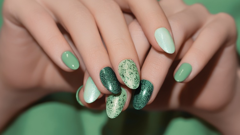 A woman's hands with the nails painted in different shades of green.