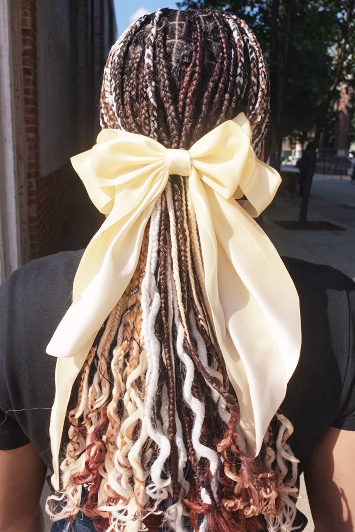 Box braids with French curls and a large satin bow