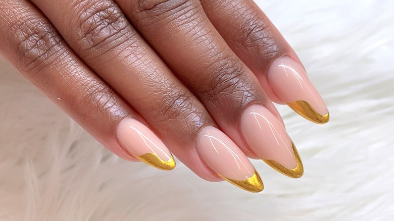 A manicure with gold tips on a nude-pink base.