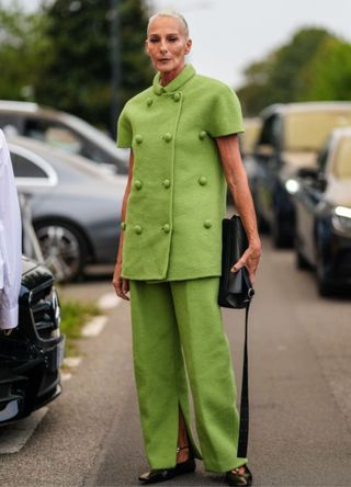 A guest wears a light green buttoned Jil Sander jacket, a light green loose Jil Sander jacket, a shiny black leather bag, and shiny black ballerina flats leather shoes, outside Jil Sander, during the Milan Fashion Week Spring/Summer 2024-2025 on September 18, 2024, in Milan, Italy