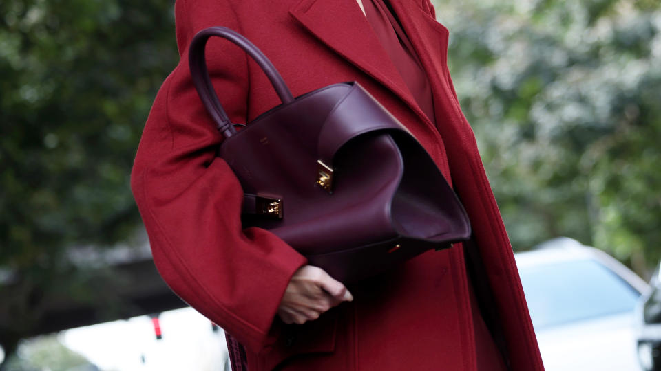 Leonie Hanne wears red long dress, red coat, burgundy Ferragamo designer bag during the Milan Fashion Week Menswear Spring 2025 runway show on September 21, 2024 in Milan, Italy.