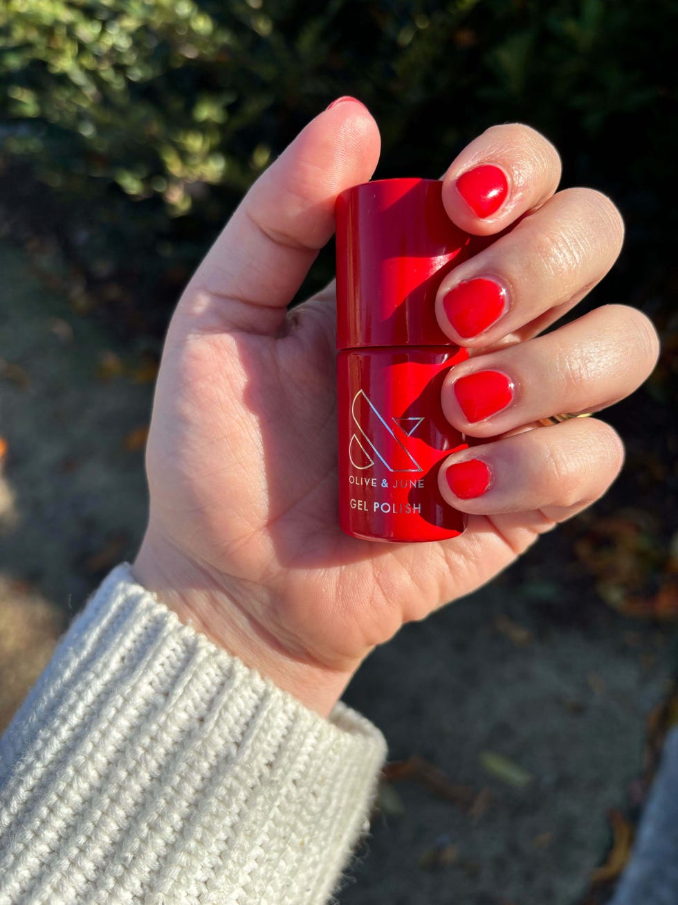 nails painted red holding a red bottle of nail polish