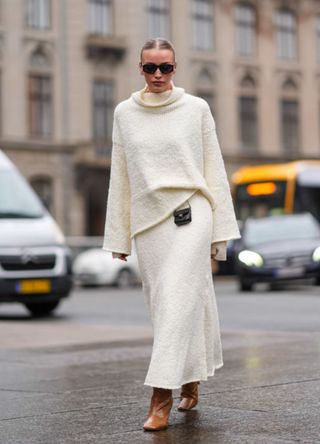 A guest wears sunglasses, a white ribbed wool 1975243076turtleneck pullover, a mini Chanel bag, midi skirt , brown leather high heels boots, outside Aeron, during the Copenhagen Fashion Week AW24 on January 30, 2024 in Copenhagen, Denmark