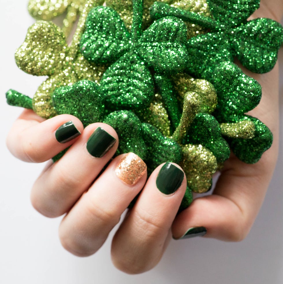 st patricks day nail ideas dark green gold glitter a person with a green and gold manicure holding a glittery clovers for st patricks day