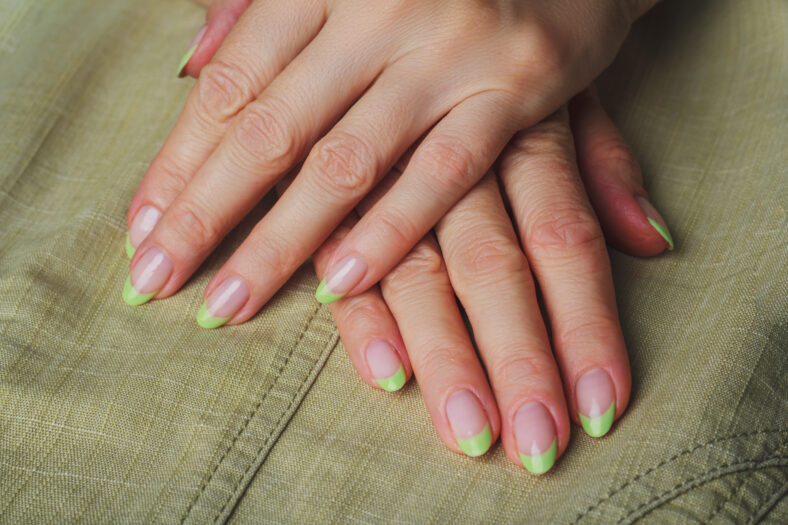 French nail art in light green colour on clothes background