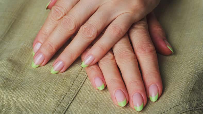 French nail art in light green colour on clothes background