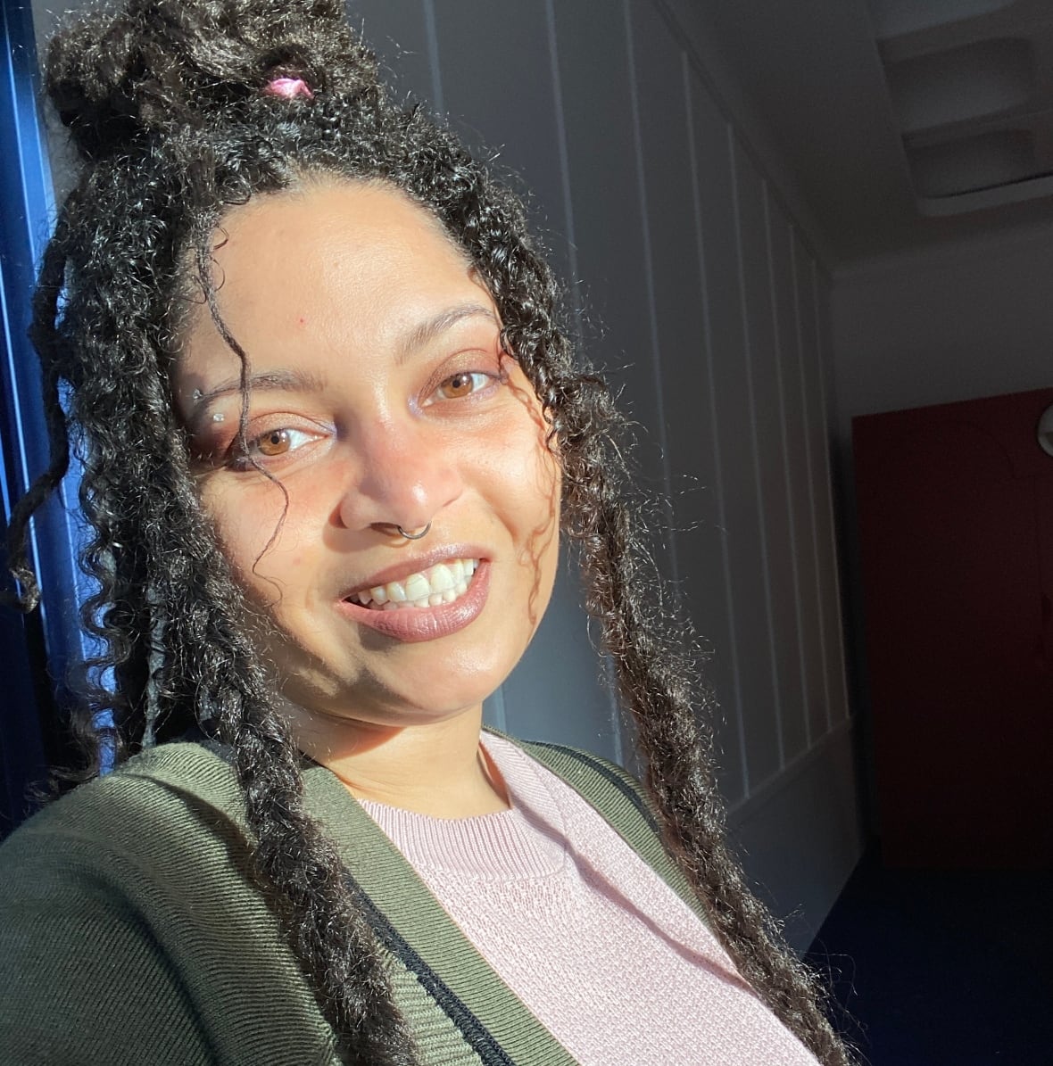 A woman with an intricate hairstyle -- the top half gathered and longer braids and curls falling around her head -- smiles at the camera.