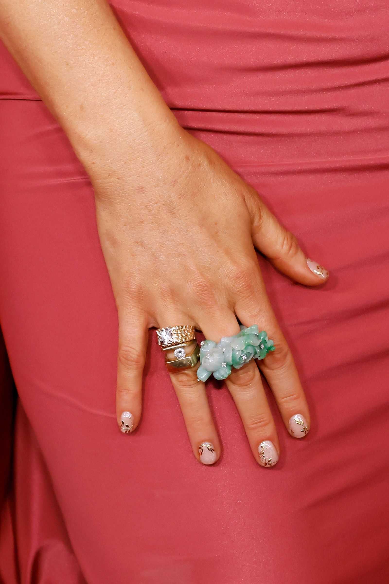 Blake Lively's hand is shown. She wears short nails with gold nail art.