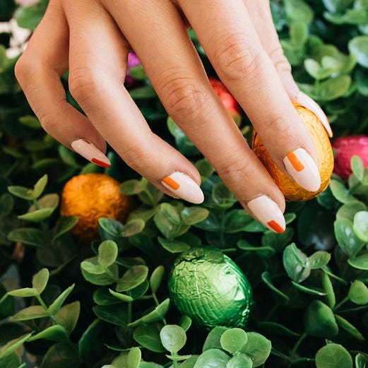 a person with painted fingernails in peach and orange picking up some easter candy