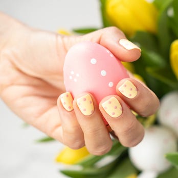 woman with yellow manicure holding an easter egg, bunch of tulips in the background
