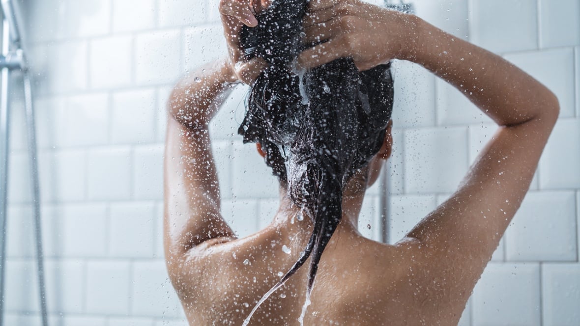 A woman washes her hair in the shower.